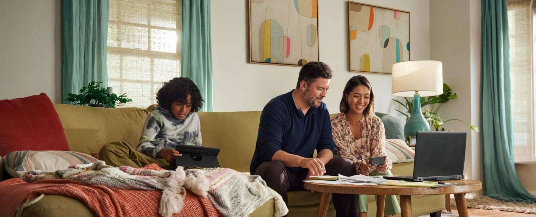 a family sitting on a couch looking at a laptop computer