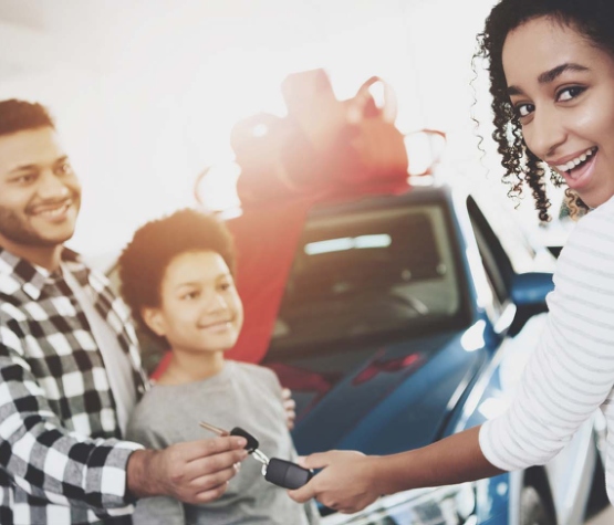a family of three getting keys to a new vehicle
