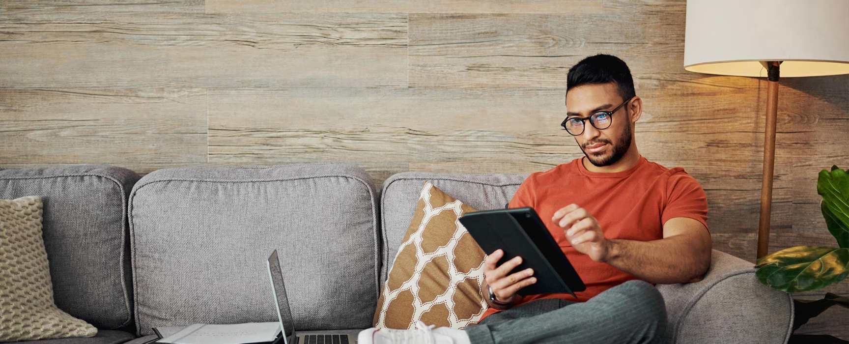 a man sitting on his couch viewing his tablet
