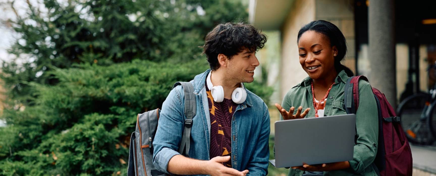 two students talking while looking at a laptop computer